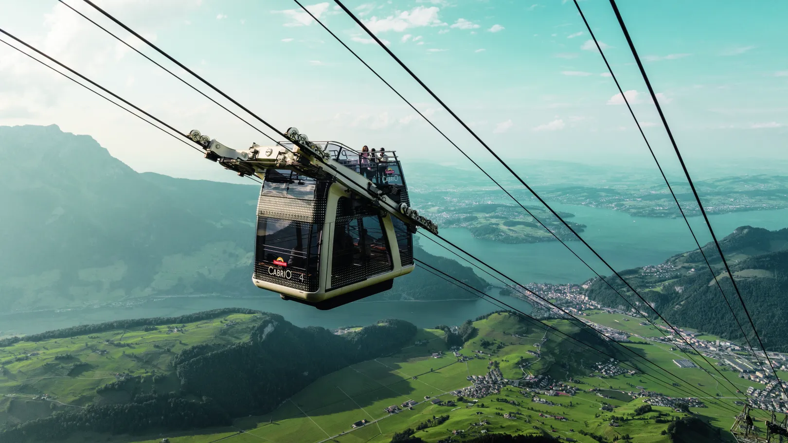 Le téléphérique CabriO descend de la station de montagne, offrant une vue sur les vallées verdoyantes, le lac des Quatre-Cantons et le paysage montagneux environnant.